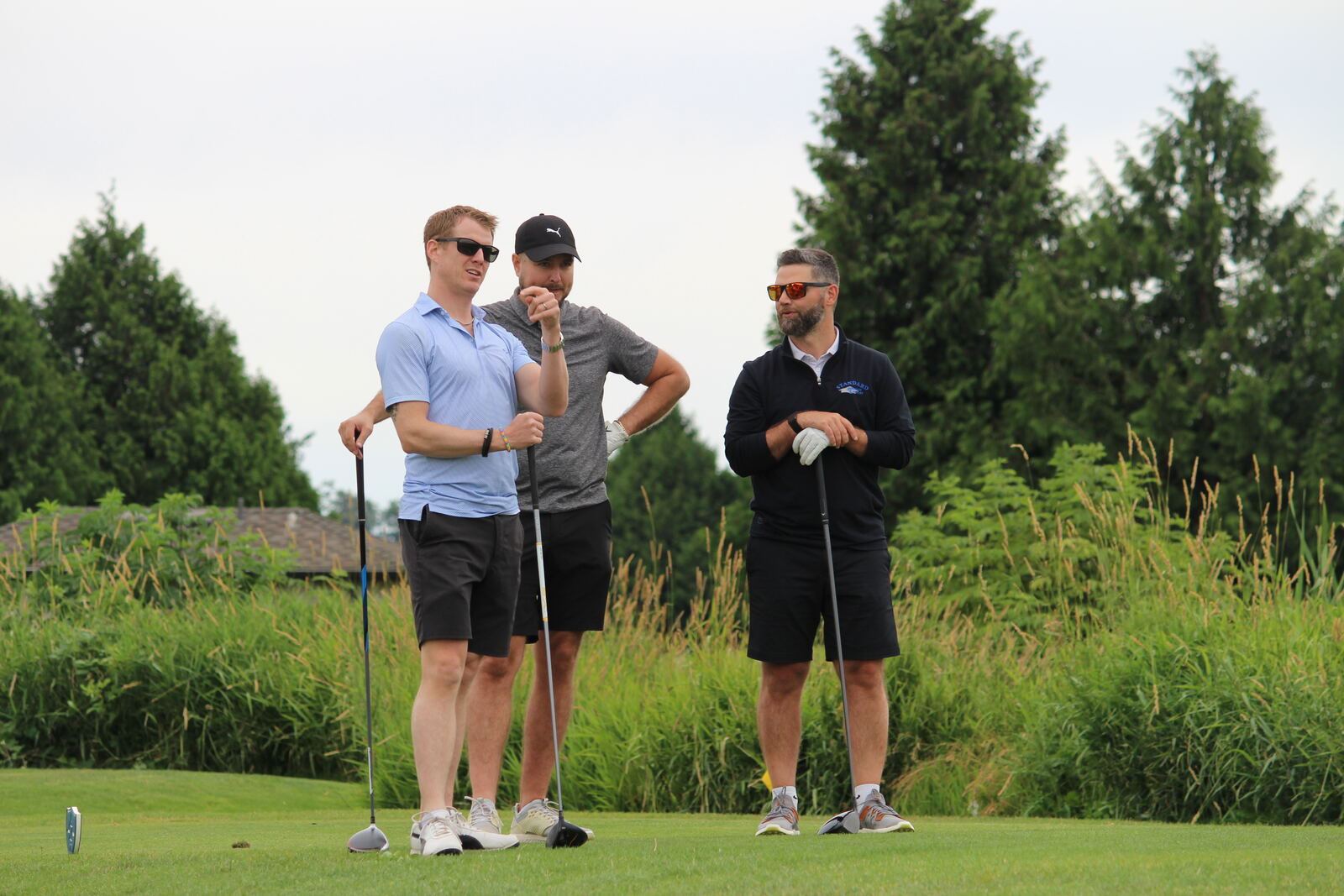 Three golfers talking strategy on the tee box