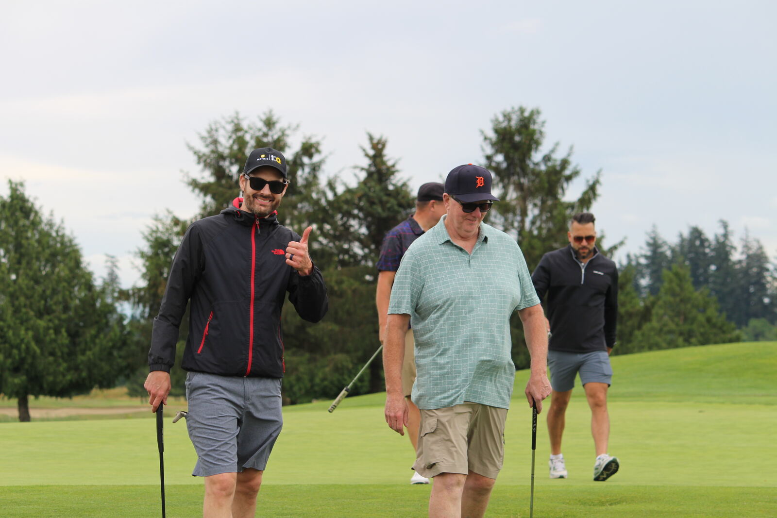 Golfers walking off the green, one giving a thumbs up