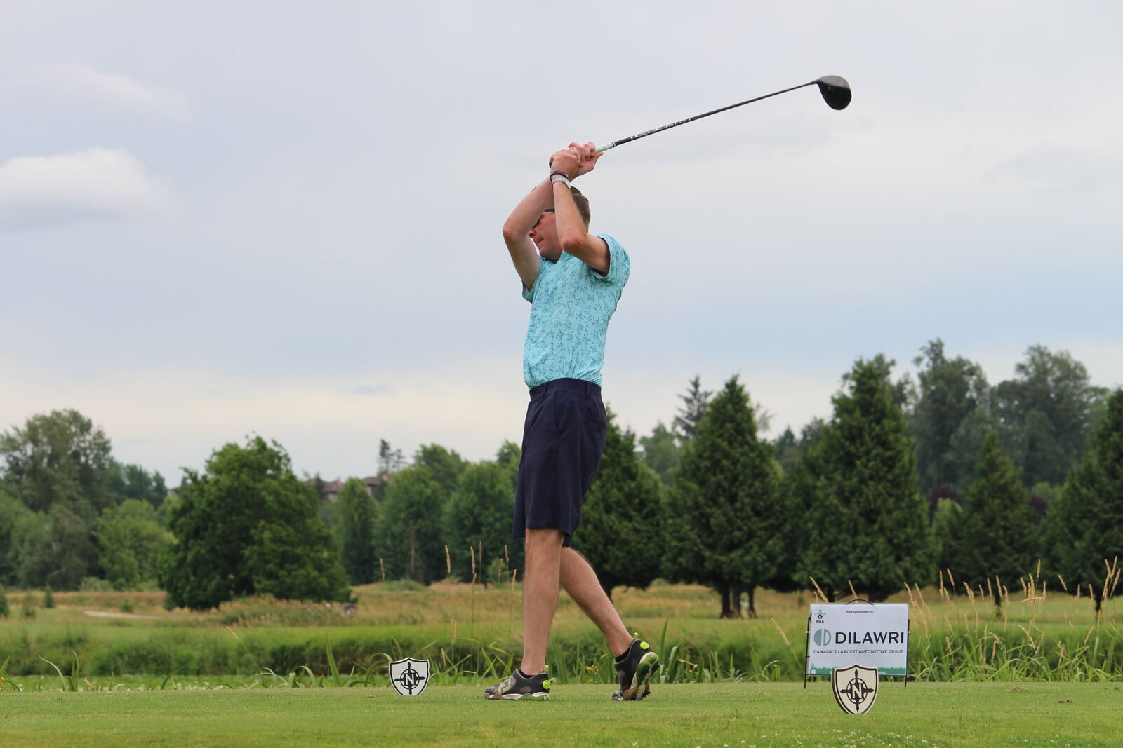 A golfer at the top of his swing on a sponsored tee box