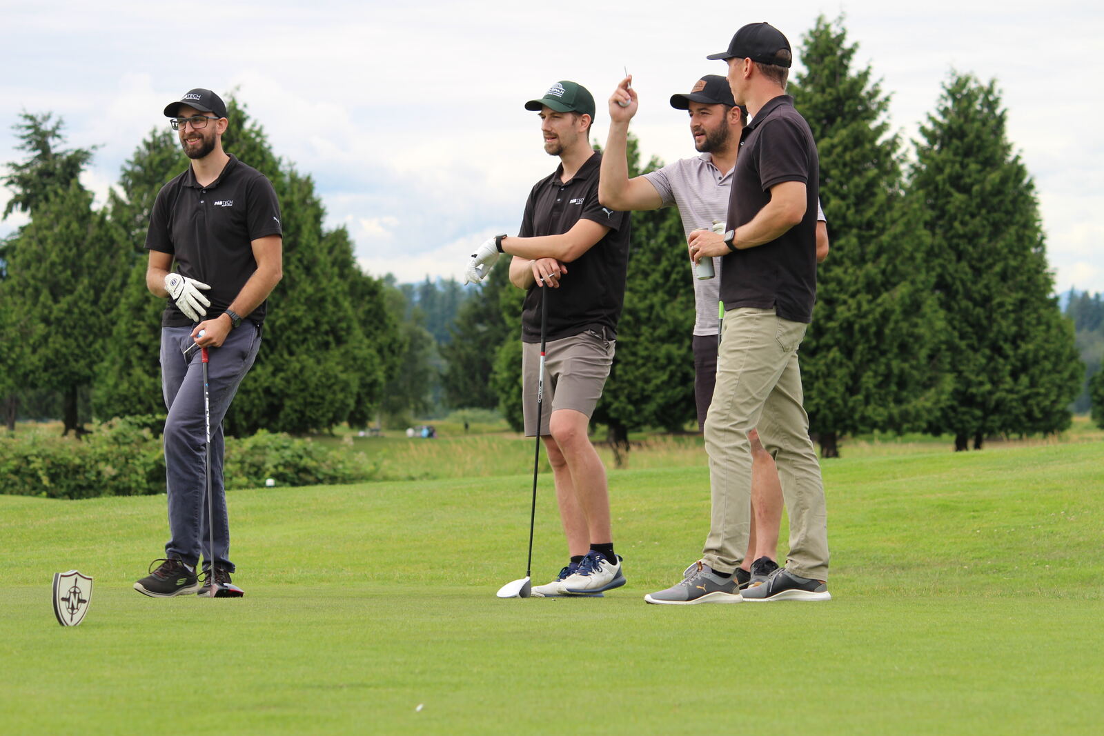 A foursome watching a drive from the tee box
